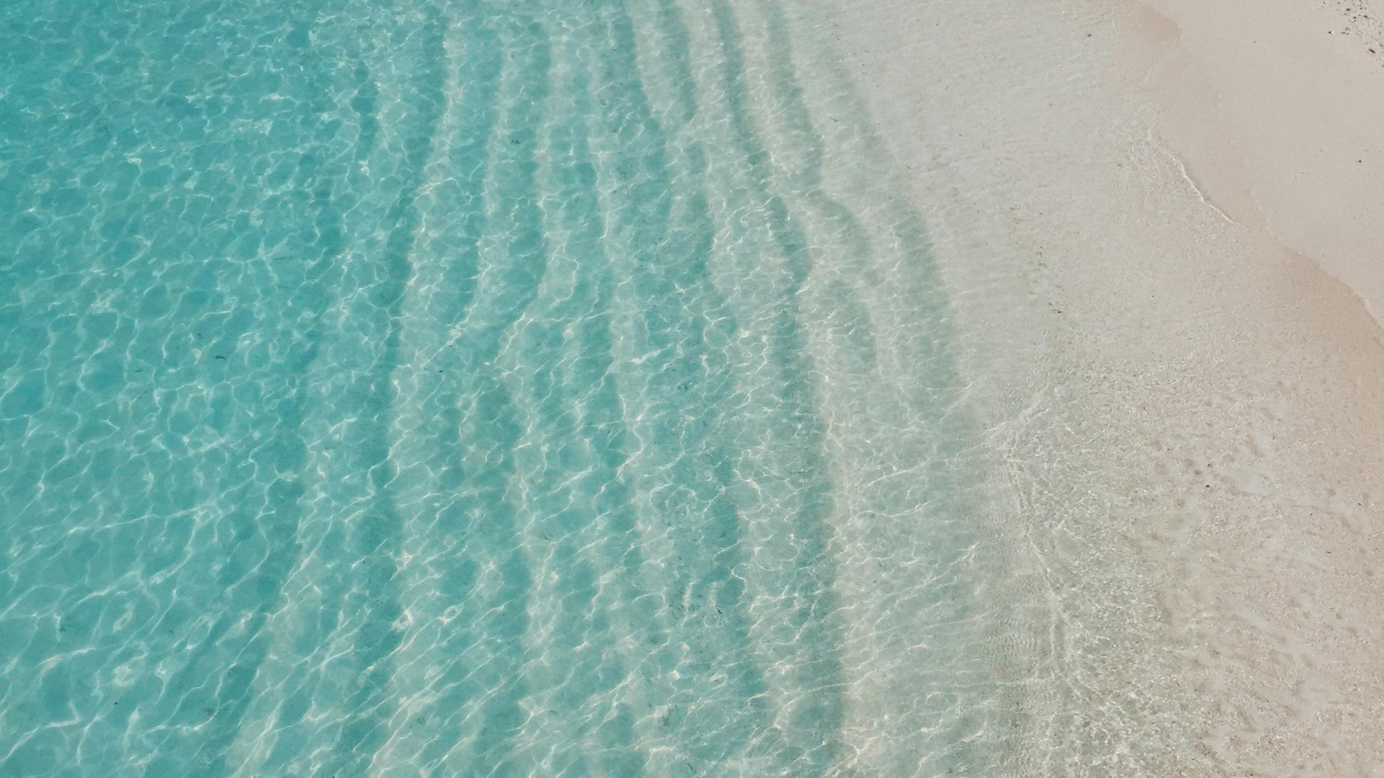 Seafoam ripples running into pale sand, from above