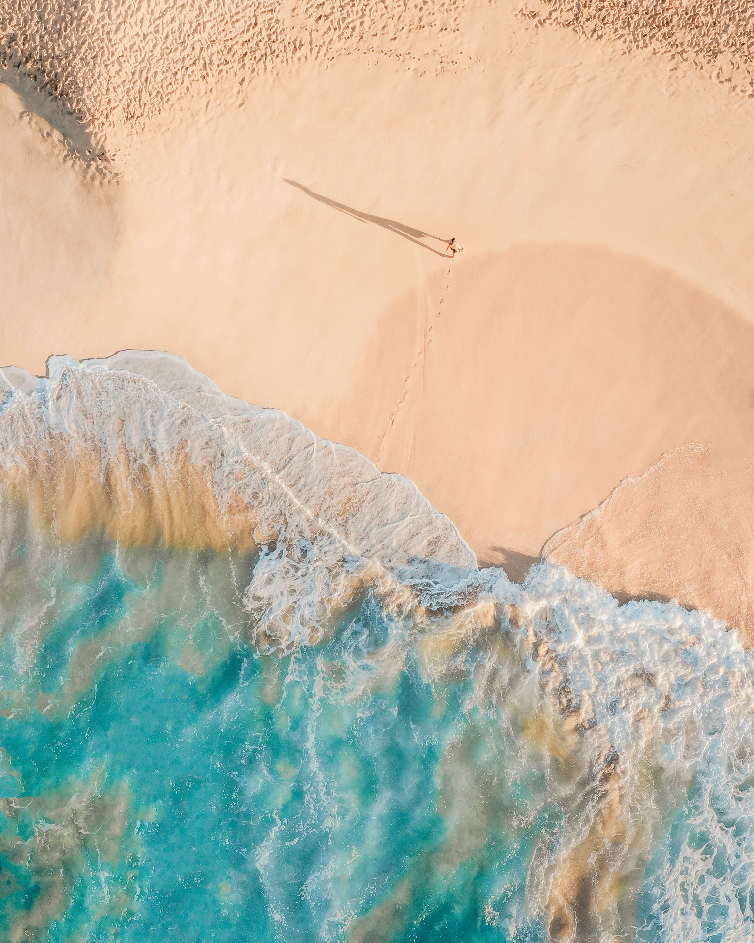 A swimmer walking out of turquoise water onto white sand
